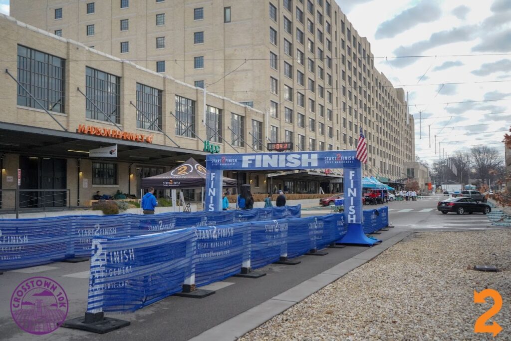 A finish line with a blue barrier at the end of races in front of a building.
