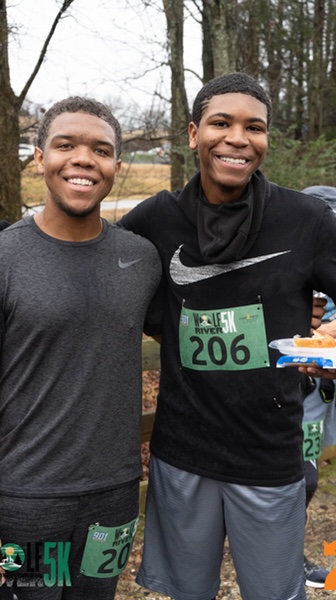 Two young men standing next to each other at a race.