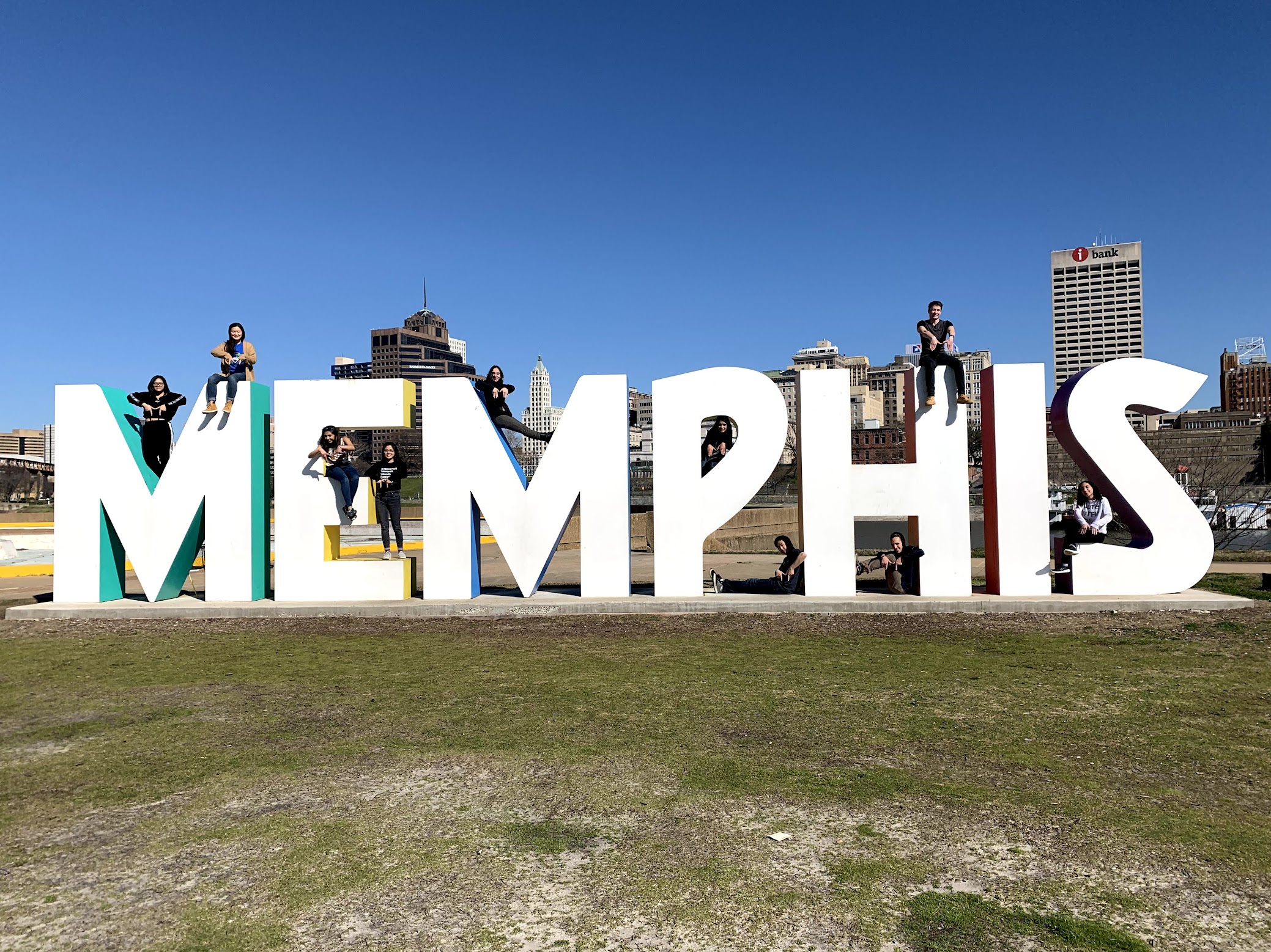 A group of people celebrating their spring break on top of a Memphis sign.