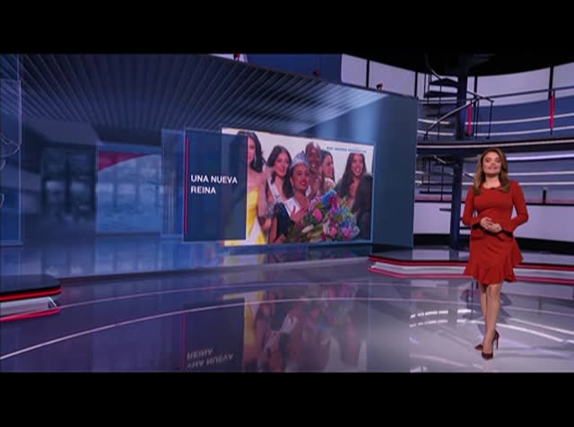 A television studio with a presenter in a red dress walking past a screen displaying an image of the Latinx community in Memphis celebrating, captioned "una nueva reina.
