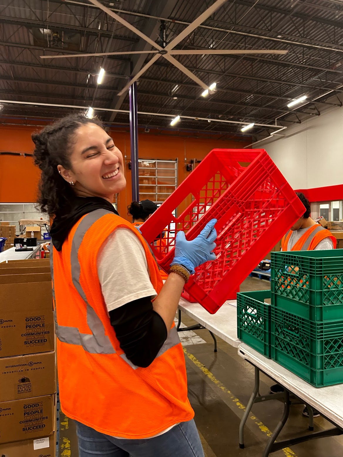 A woman holding an orange crate in a warehouse during spring break.