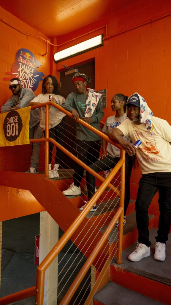 Group of five people posing together on a stairwell with vibrant orange walls for the Red Bull Dance Your Style event.