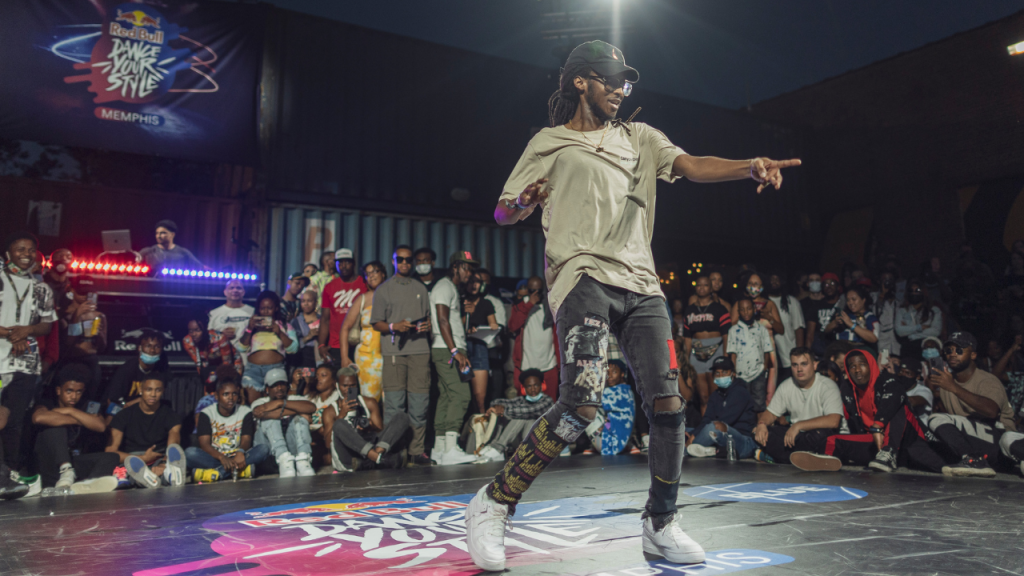 A dancer performing at the Red Bull Dance Your Style street dance competition, with an audience watching in the background.
