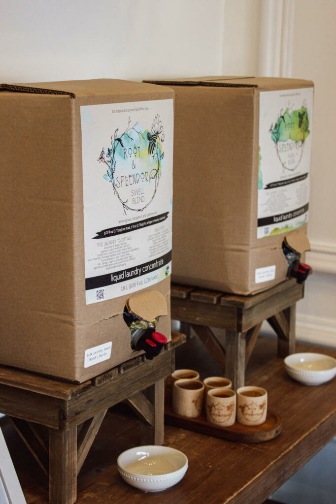 Cardboard boxes of sustainable liquid laundry concentrate displayed on wooden stools, with product information labels visible.